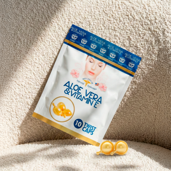 Empaque tipo doypack blanco con dorado y azul metalizado del producto aloe vera and vitamin e ladeado en un fondo de tela rugosa con dos softgels a los lados