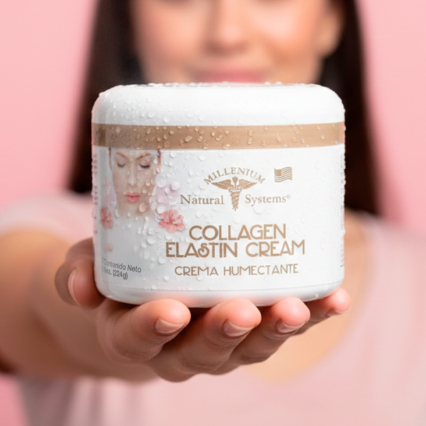 Mujer vestida de rosa sonrie mientras sostiene en primer plano un frasco blanco con dorado de collagen elastin cream