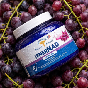 Tarro azul del suplemento Natural MNS ENERNAD sabor uva con gotas de agua condensada, ambientado sobre un fondo de racimos de uvas naturales.